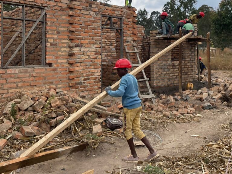 Ragazzo trasporta una trave nel cantiere di riqualificazione